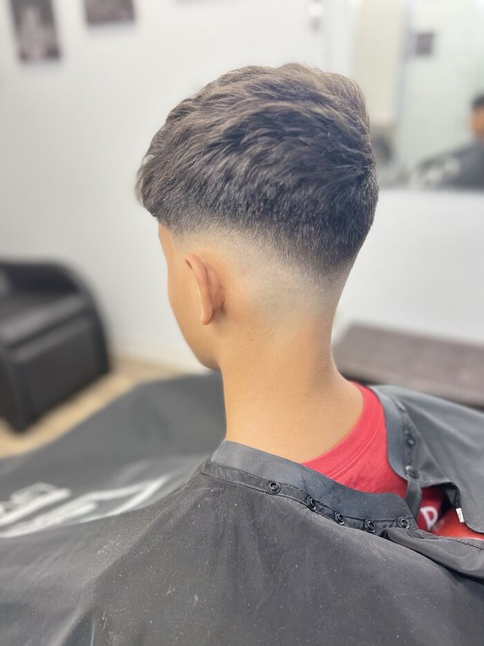 Low taper fade with a natural textured top, back view, Royal Palm Beach FL