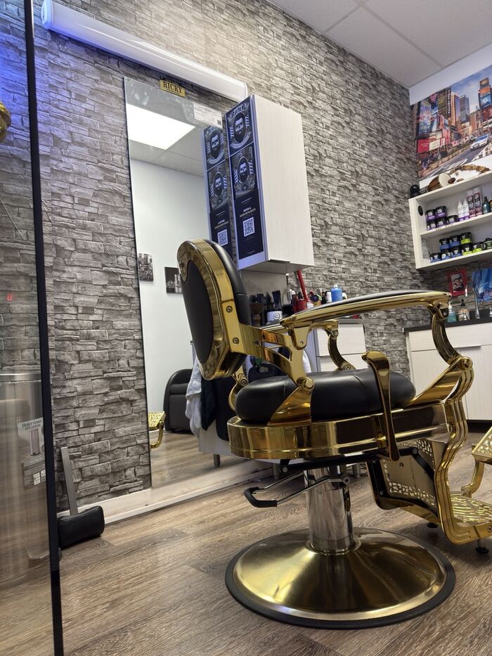 Ricky's Style private barbershop suite in Royal Palm Beach, FL — gold barber chair, stone wall and mirror
